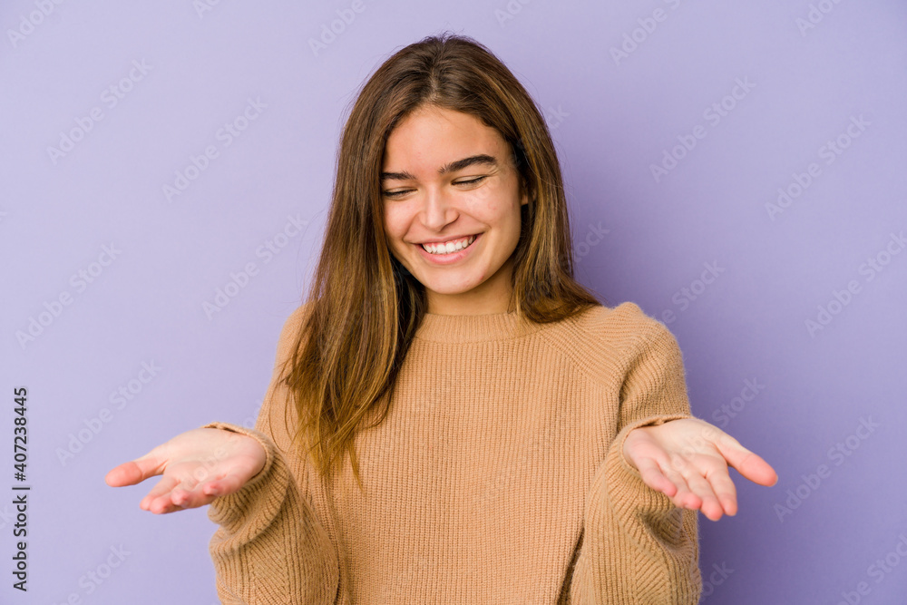 Young skinny caucasian girl teenager on purple background holding something with palms, offering to camera. Young skinny caucasian girl teenager on purple background holding something with palms, offering to camera.