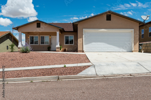 The facade of a suburban house with garage and driveway, in a suburb in the outskirts of the city of Gallup, New Mexico, USA