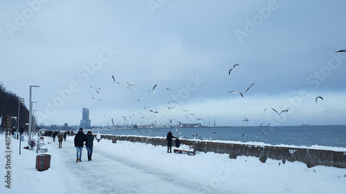 Winter walk. People walking on the Baltic sea boulevard in Gdynia, Poland. Gdynia is an important seaport of Baltic Sea in Poland. © abrada