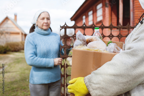 Courier delivering shopping to senior woman with face mask, corona virus and quarantine concept photo