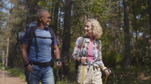 Cheerful senior caucasian couple hiking in park with backpacks, enjoying adventure © nimito