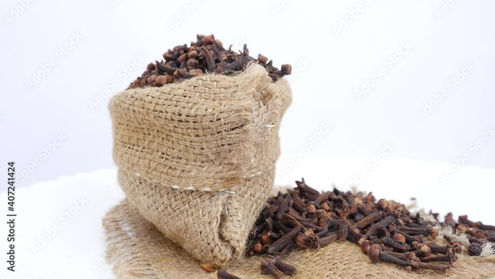 Rotating shot of bag filled with cloves and cloves scattered Rotating shot of bag filled with cloves and cloves scattered