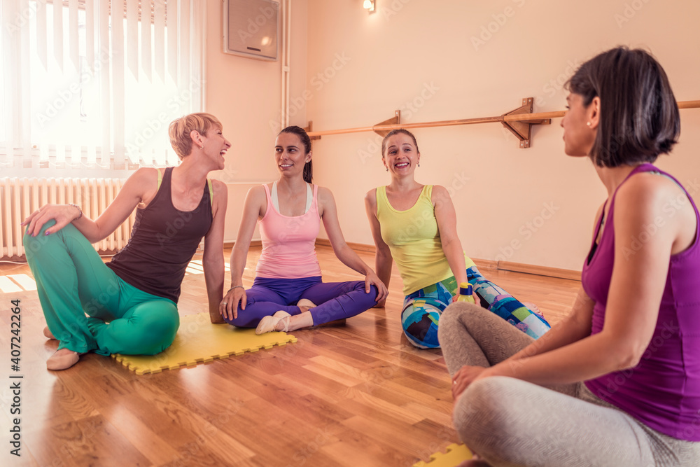 Beautiful adult women doing exercises on stretching ballet bar in Pilates class. Group of females doing yoga, pilates and fitness exercise indoors in studio. Beautiful adult women doing exercises on stretching ballet bar in Pilates class. Group of females doing yoga, pilates and fitness exercise indoors in studio.