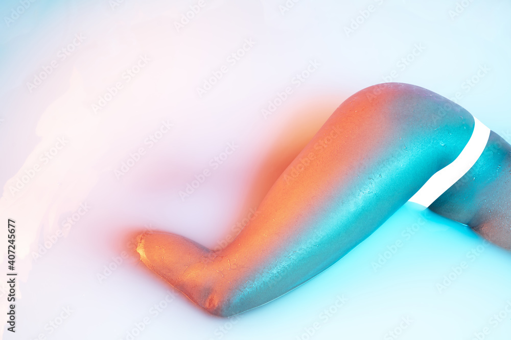 Flexible. Close up female body in the milk bath with soft white glowing in neon light. Copyspace for advertising. Modern neoned colors, foam. Beauty, fashion, style, bodycare concept. Attractive. Flexible. Close up female body in the milk bath with soft white glowing in neon light. Copyspace for advertising. Modern neoned colors, foam. Beauty, fashion, style, bodycare concept. Attractive.