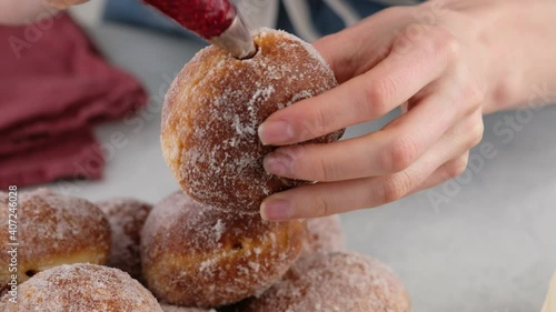 Berliners. Female hands lay donuts on a rectangular plate on a white background. Delicious sweet donuts. Making donuts with jam.