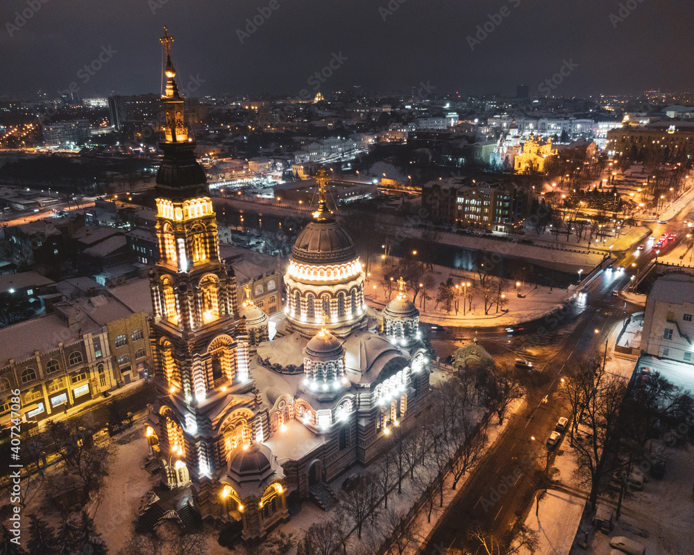 Holy Annunciation Cathedral illuminated in winter snowy night lights. Aerial view Kharkiv city orthodox church landmark , Ukraine. Side view from air. Color graded