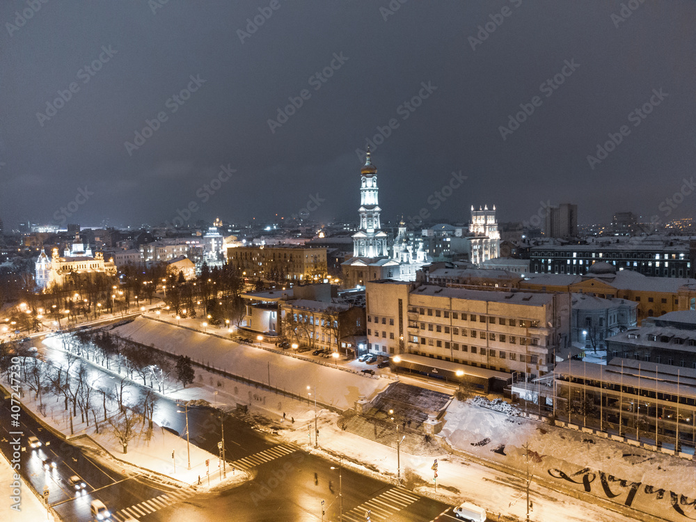 Obraz premium Winter snowy evening lights illuminated city aerial landscape. Dormition Cathedral, Serhiivskyi Maidan in Kharkiv downtown, Ukraine