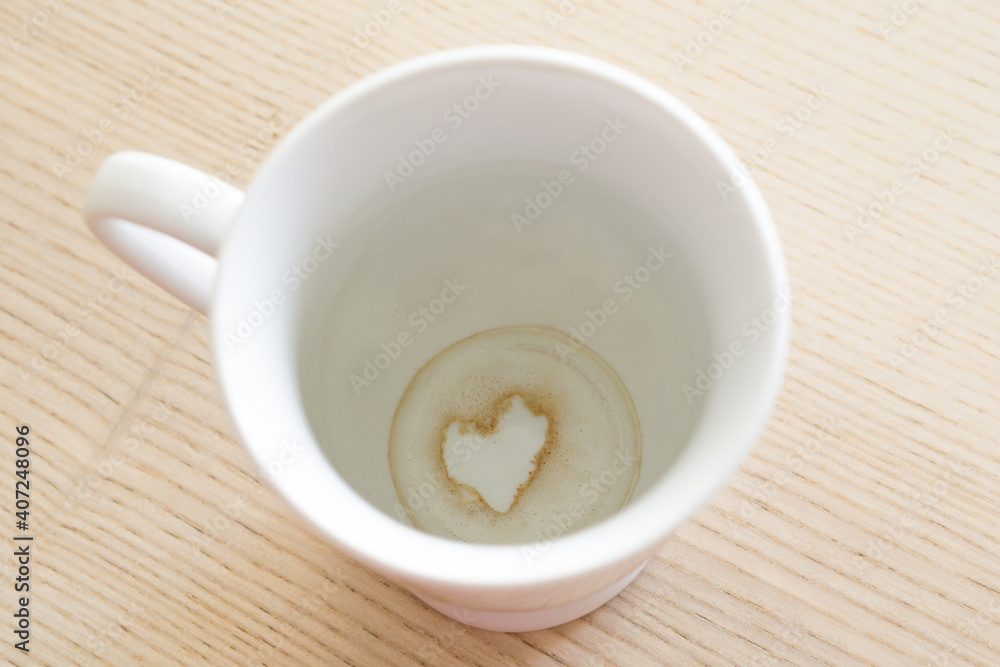 A cup of tea with the grounds at the bottom of it creating the silhouette of a heart