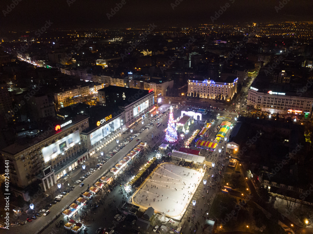 Freedom Svobody Square (Kharkiv) aerial view at night with New year holidays and Christmas tree decorations with colorful illumination in city center recreation area.