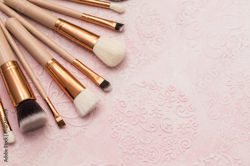 Soft, clean makeup brushes with natural lint on a beige background. The view from the top.