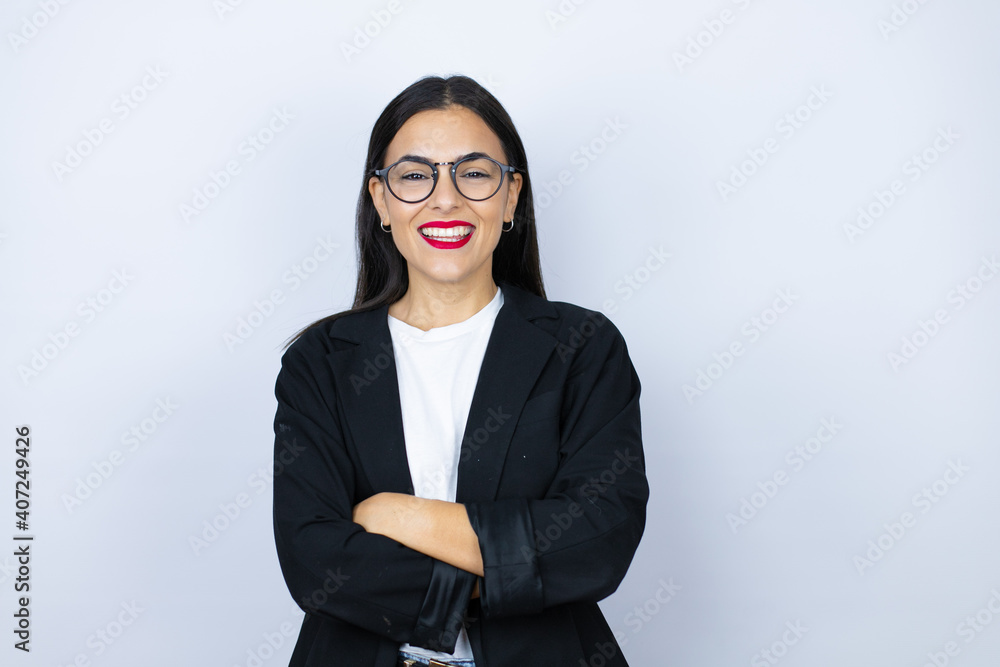 Young business woman standing and smiling with a confident smile showing teeth with arms crossed