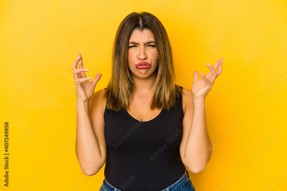 Young indian woman isolated on yellow background screaming with rage. Young indian woman isolated on yellow background screaming with rage.