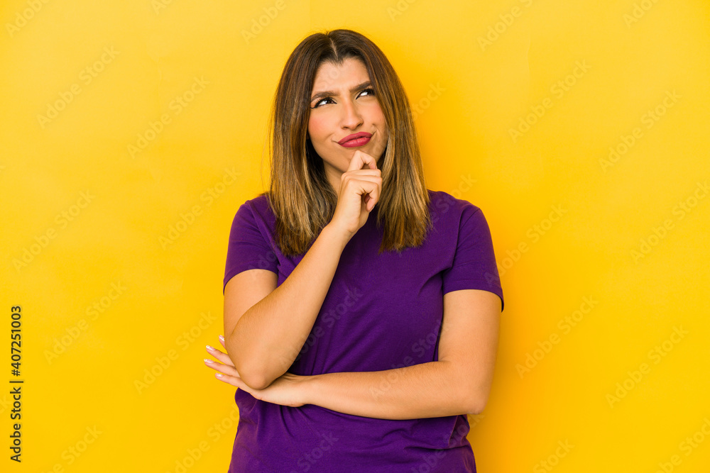 Young indian woman isolated on yellow background looking sideways with doubtful and skeptical expression. Young indian woman isolated on yellow background looking sideways with doubtful and skeptical expression.