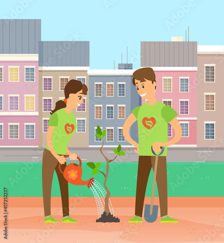 Two smiling volunteers planting tree. Man holding shovel, woman watering. People working in garden. Couple of gardeners, farmers planting seedling in the park against the background of city buildings