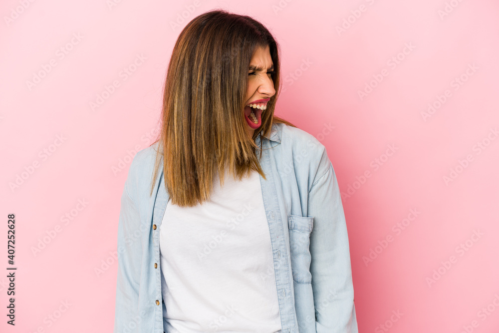 Fototapeta premium Young indian woman isolated on pink background shouting very angry, rage concept, frustrated.