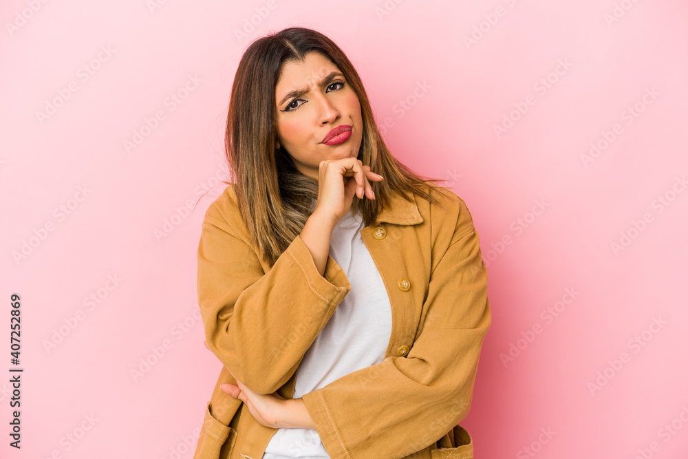 Young indian woman isolated on pink background suspicious, uncertain, examining you. Young indian woman isolated on pink background suspicious, uncertain, examining you.
