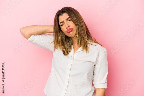 Young indian woman isolated on pink background having a neck pain due to stress, massaging and touching it with hand.