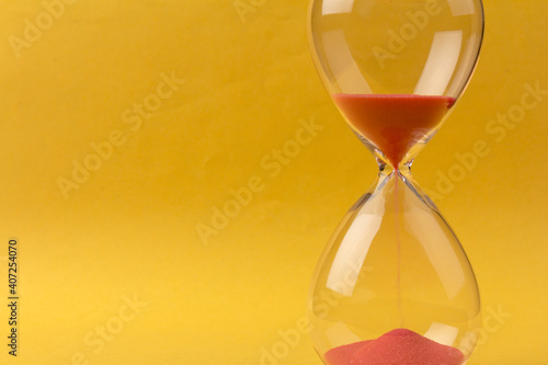 Crystal hourglass on yellow background as a concept of passing time for business term, urgency and outcome of time.