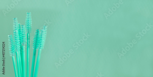 Mint color makeup eyebrow brushes on background. Eyebrow and eyelash combs. Disposable pink brush for eyelashes and eyebrows. Copy space.