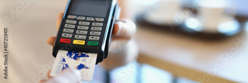 The waiter holds a wireless terminal to pay the bill. The client in the cafe pays by credit card photo