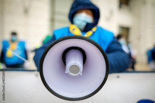 Shallow depth of field (selective focus) with details of a bullhorn held by a man during a political/social issues rally.