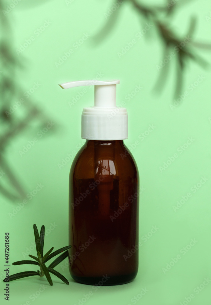Brown glass bottle with a pump of cosmetic products framed by green leaf branches, green background. Natural organic spa cosmetic beauty concept. Front view Mock up. Brown glass bottle with a pump of cosmetic products framed by green leaf branches, green background. Natural organic spa cosmetic beauty concept. Front view Mock up.