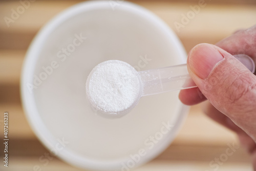 Man holding a scoop with D-ribose powder inside photo