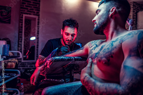 Tattoo artist in black gloves making a tattoo on the arm of man © Vladimir Borovic