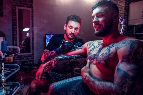 Bild auf Leinwand Tattoo artist in black gloves making a tattoo on the arm of man