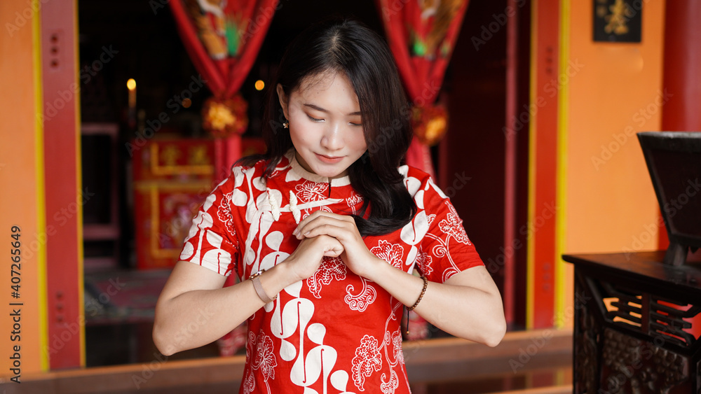 Asian Chinese woman in a cheongsam dress with congratulations gest at vihara Asian Chinese woman in a cheongsam dress with congratulations gest at vihara