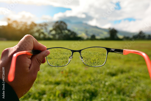 hand holding lenses showing a person's focus and myopia, seeing nature