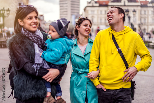 Group of young happy people with baby laughing and walking in the street