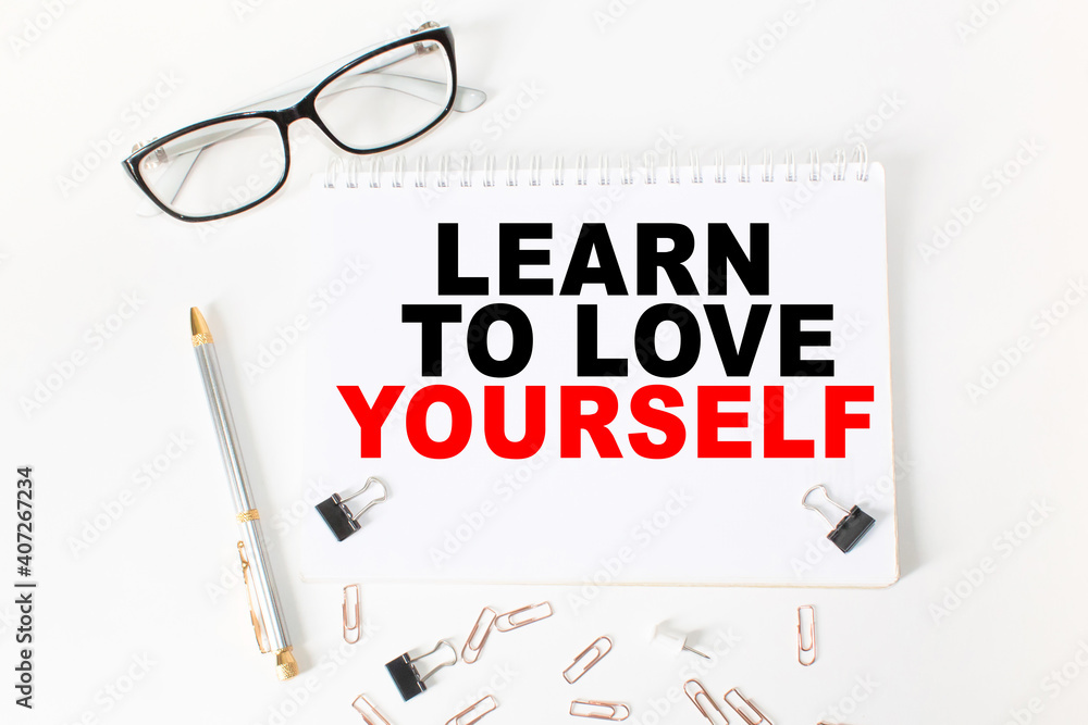 Notepad with inscriptions LEARN TO LOVE YOURSELF on a white background. business concept. Notepad with inscriptions LEARN TO LOVE YOURSELF on a white background. business concept.