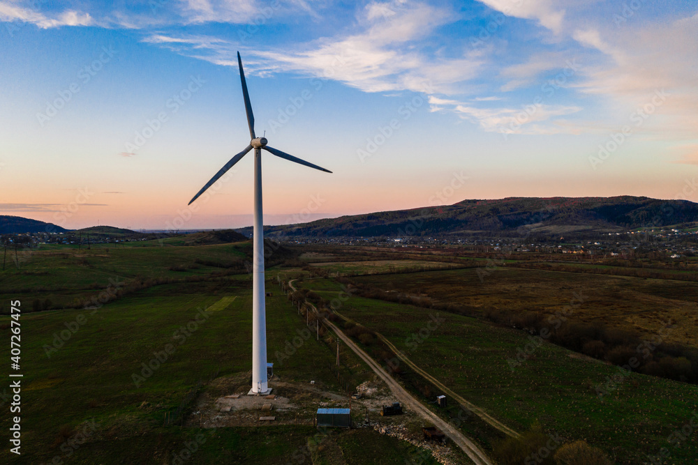 One windmill in the field, production of environmentally friendly energy, the beginning of wind energy production in Ukraine, a windmill against the backdrop of the sunset.