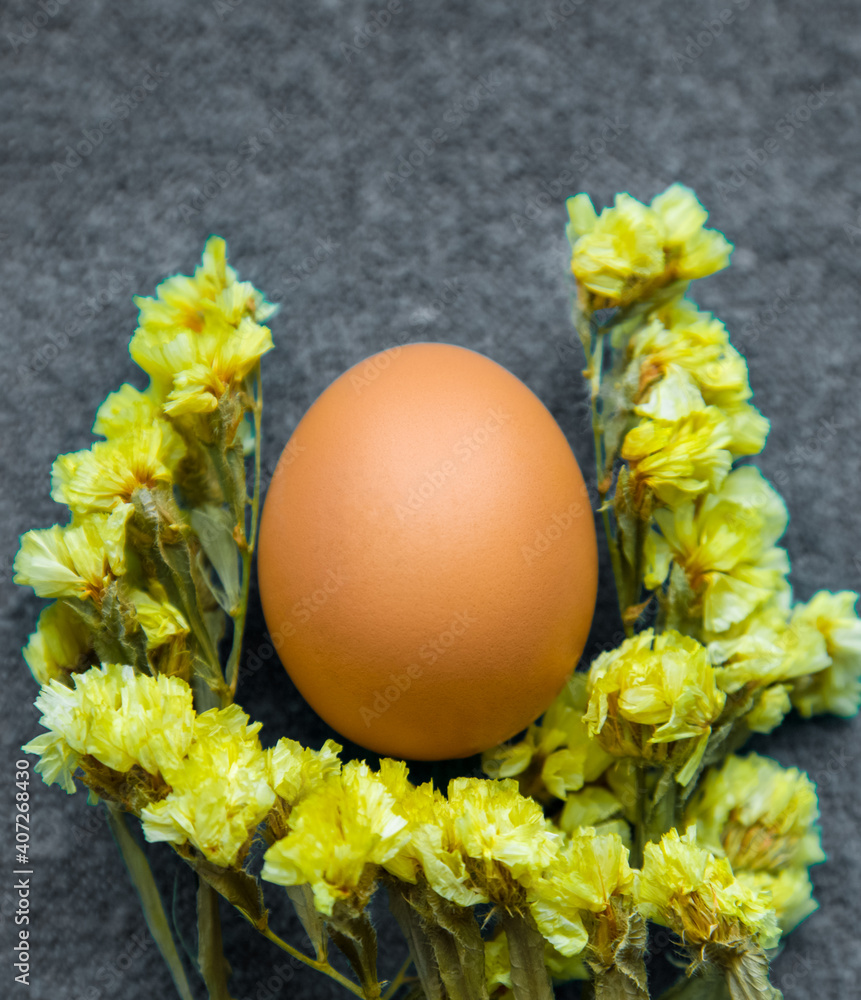 Easter egg and yellow flowers on a gray background. Color trend 2021. Vertically - obrazy, fototapety, plakaty 