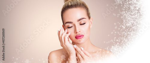 Young beautiful woman over beige background with snow and snowflakes. Cryolifting concept. photo