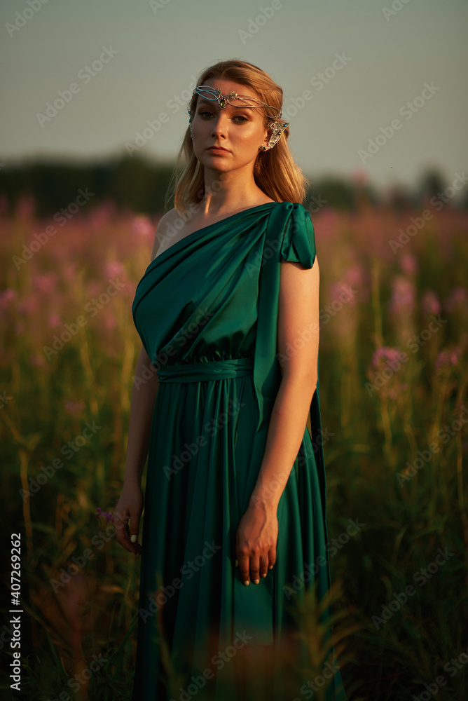 Obraz premium Young beautiful girl with a bouquet of flowers in her hands at sunset.