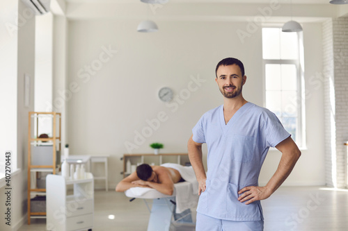 Young smiling confident man professional chiropractor masseur standing and looking at camera