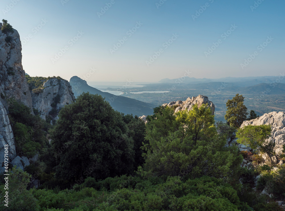 View from Baunei viewpoint on green landscape with trees, limestone rocks, Arbatax penisula and mediterranean sea. Sardinia, Italy. Summer blue sky View from Baunei viewpoint on green landscape with trees, limestone rocks, Arbatax penisula and mediterranean sea. Sardinia, Italy. Summer blue sky