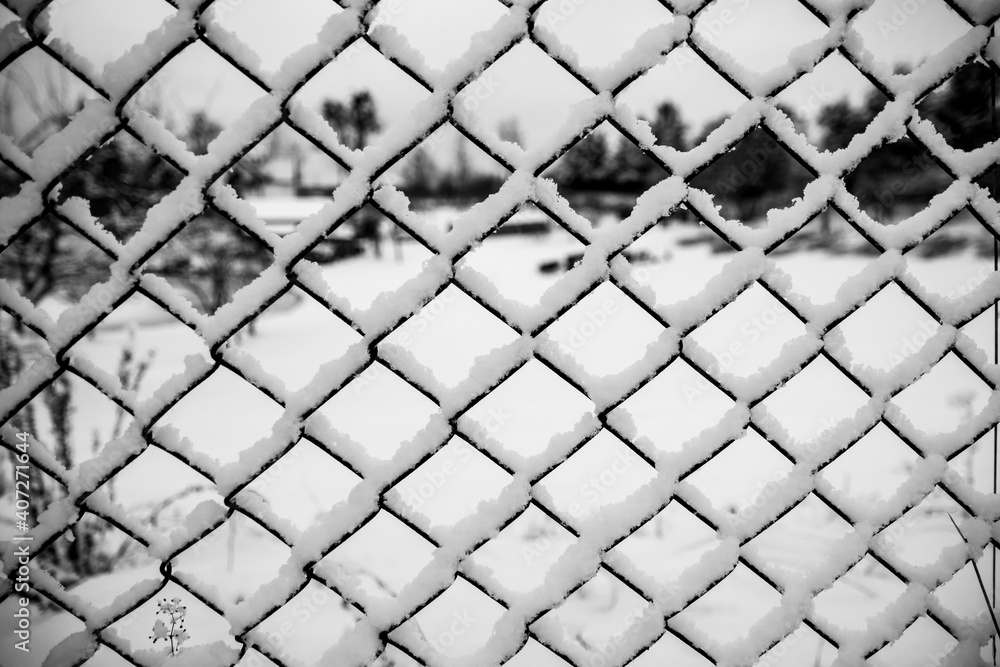 Fototapeta premium Snow lying on a chain link fence, winter background