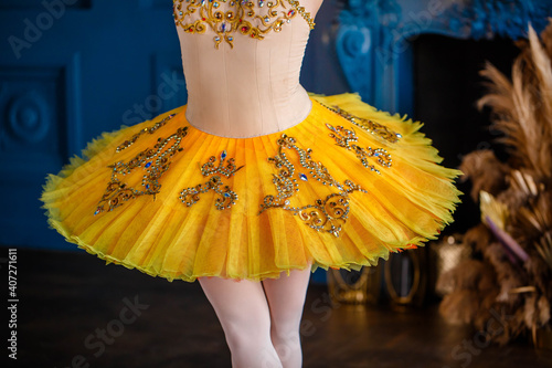 Ballerina in a yellow tutu on pointe dancing in a beautiful dark hall