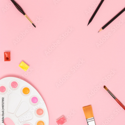 Frame made of tools for painting on a pink pastel background. Creativity concept with copyspace.