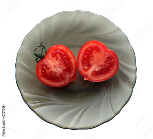 two halfes of  red tomato in shape of hearts on a plate isolated on white. Valentine's Day concept.