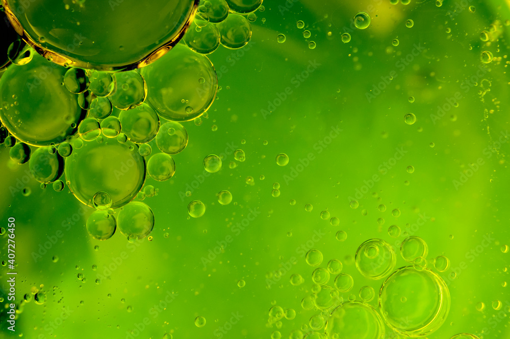 Oil in water emulsion, greasy drops and abstract backgrounds concept with fat droplets forming bubbles due to surface tension on green background