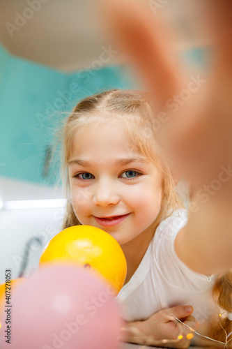 A girl of seven years old is wearing a white T-shirt. Plays with ripe tangerines