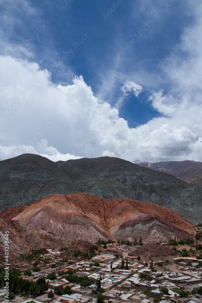 Beautiful view of Purmamarca village at the foot of the popular Seven Color Hill. Aerial view of the buildings and houses with the colorful mountains in the background under a magical sky.