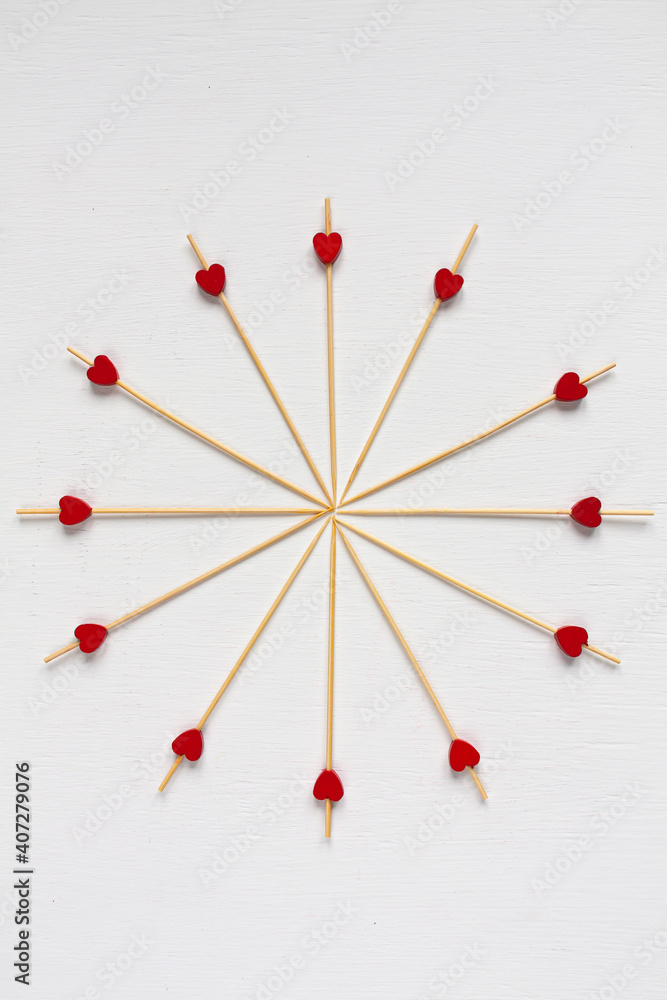 small red hearts on wooden sticks laid out in a circle on white background small red hearts on wooden sticks laid out in a circle on white background