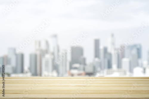 Empty wooden table top with beautiful blurry skyscrapers at daytime on background  mock up