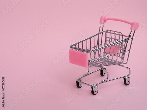 Small empty shopping cart on pink background