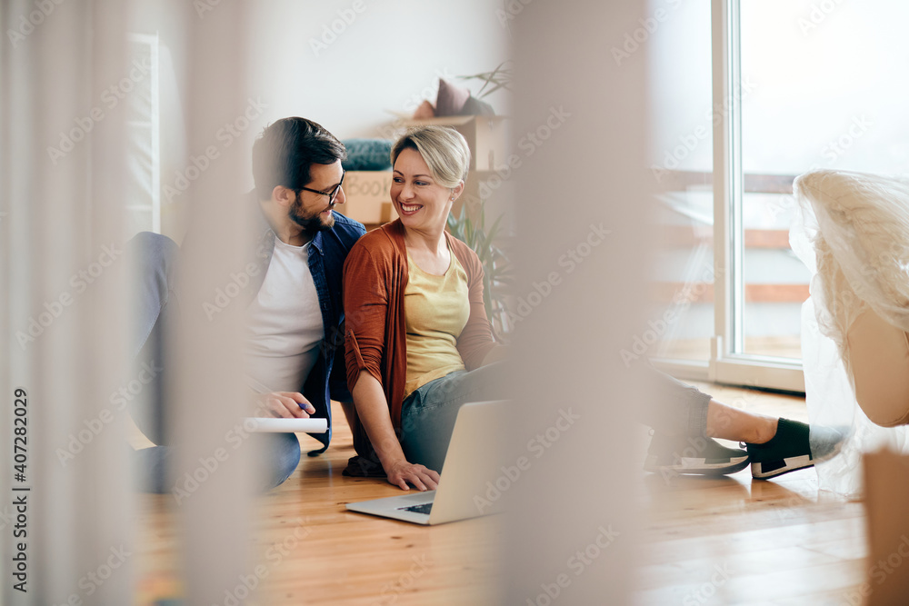 Happy couple talking while using laptop at their new apartment. Happy couple talking while using laptop at their new apartment.